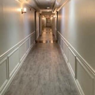 A long, well-lit hallway with elegant wall paneling and wooden flooring.