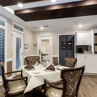 A modern dining room with an elegant table setting and comfortable chairs, featuring a stylish ceiling design and wooden flooring.