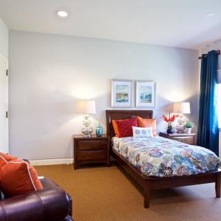 A cozy bedroom with a single bed, vibrant decor, and warm lighting.