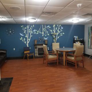 A cozy living space featuring a blue accent wall with decorative trees, comfortable seating, and a dining area.