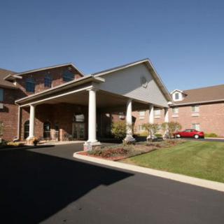 A brick building with a covered entrance and landscaped surroundings.