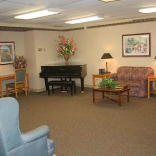 A cozy living room with a piano, sofa, chairs, and decorative elements.