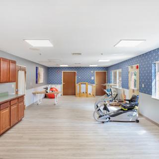 A spacious rehabilitation room featuring modern furniture and a calming blue color scheme.
