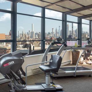 A gym with exercise equipment overlooking a city skyline.