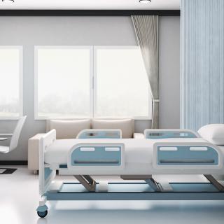 A modern hospital room with a patient bed and large windows.