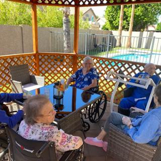 A group of seniors enjoying time together in a gazebo by the pool.