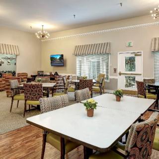 A spacious dining area with tables and chairs arranged neatly, featuring a television and decorative plants.