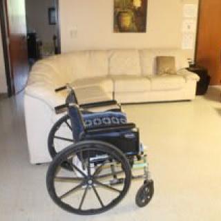 A wheelchair in a living room with a white sofa in the background.