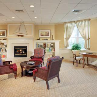 A cozy living room with a fireplace, armchairs, and bookshelves.