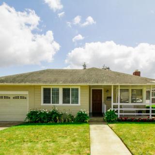 A single-story suburban house with a neatly maintained front yard under a partly cloudy sky.