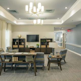 A modern living room with a seating area, TV, and chandelier lighting.