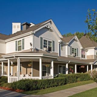 A charming residential house with a front porch and well-maintained landscaping.