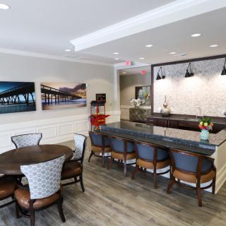 A modern and stylish kitchen-dining area featuring bar stools, a round dining table, and contemporary artwork on the walls.