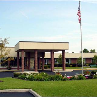 A well-maintained educational institution with vibrant landscaping and an American flag.