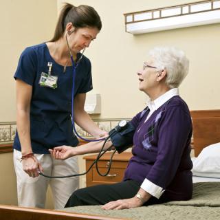 A nurse checking the blood pressure of an elderly woman in a healthcare setting.