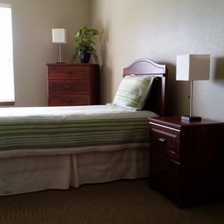 A minimalist bedroom with a single bed, nightstand, and dresser.