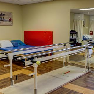 A well-equipped physiotherapy room featuring treatment beds and a parallel bar for rehabilitation exercises.
