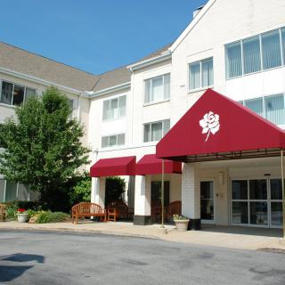 The entrance of a hotel with a red awning under clear skies.