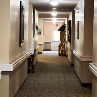 A well-lit hallway with carpet flooring, featuring walls adorned with artwork.