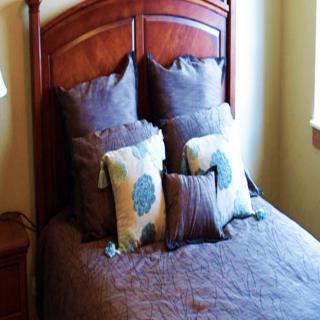 A neatly arranged bed with multiple pillows and a wooden headboard.