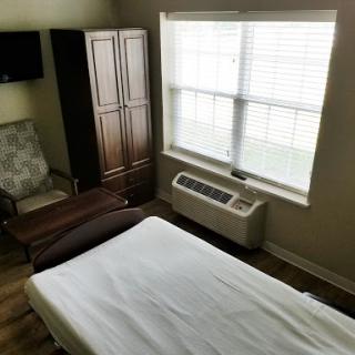 A cozy room featuring a bed, a comfortable chair, and natural light from the window.
