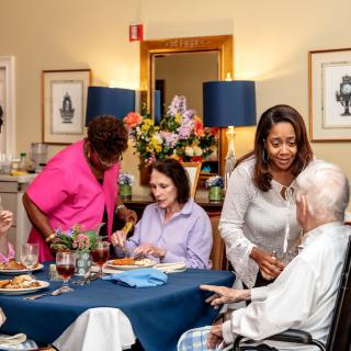 Caregivers assist seniors during a mealtime at a nursing home, fostering a warm and supportive environment.