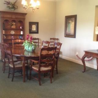 A cozy dining room with a wooden table, chairs, and a bookshelf in the background.