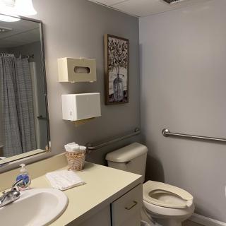 A well-organized bathroom with a sink, toilet, and handrail.
