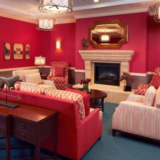 A cozy living room with vibrant red walls, featuring a fireplace, comfortable seating, and elegant decor.