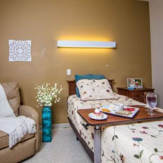 A cozy bedroom setting featuring a single bed, an armchair, and warm lighting.