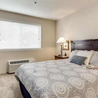 A cozy bedroom with a neatly made bed and a lamp on a bedside table.