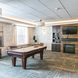A modern game room featuring a pool table, television, and fireplace.