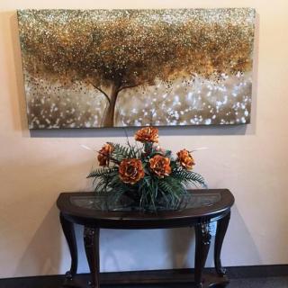 A decorative wall with a tree painting above a table adorned with orange flowers.