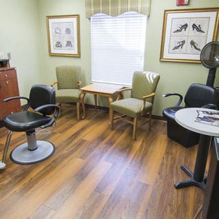 A cozy waiting area in a salon with a barber chair and comfortable seating.