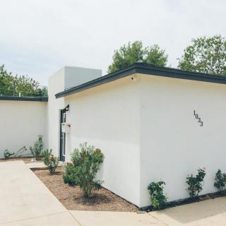 A modern minimalist house with a simple landscape and driveway.