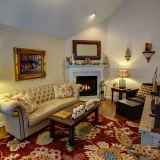 A cozy living room with a plush sofa, coffee table, and a fireplace surrounded by traditional decor.
