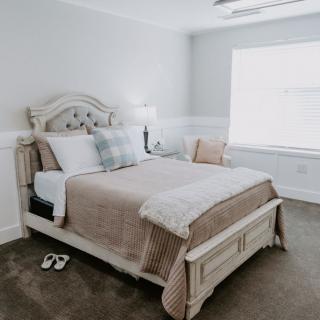 A cozy bedroom with a neatly made bed, featuring soft neutral tones and elegant decor.