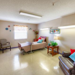 A hospital room with a bed, chairs, and decorative elements.