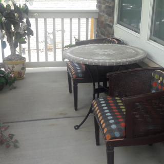 A cozy outdoor patio area with a table, two chairs, and a potted plant.