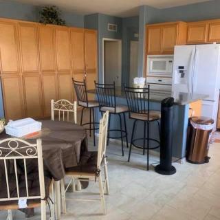 A cozy kitchen and dining area featuring wooden cabinets, a refrigerator, a table with chairs, and bar stools.