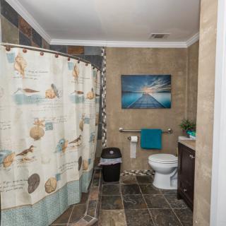 A neatly arranged bathroom with a coastal-themed shower curtain and artwork.