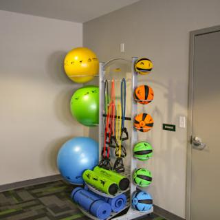 A well-organized display of various fitness equipment including balance balls, yoga mats, and resistance bands.
