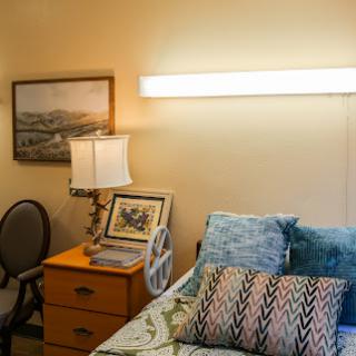 A cozy bedroom setup featuring a bed adorned with decorative pillows, a bedside lamp, and a chair.