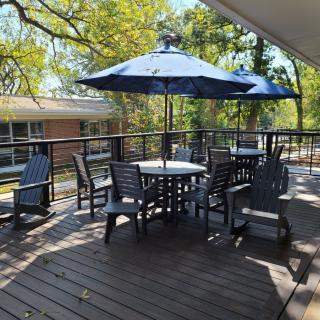 A sunny outdoor patio with tables, chairs, and umbrellas on a wooden deck.