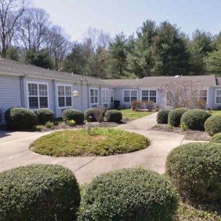 A serene courtyard with neatly trimmed bushes and a circular walkway surrounded by buildings and trees.