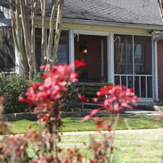 A charming residential home with a welcoming front porch framed by vibrant flowers.
