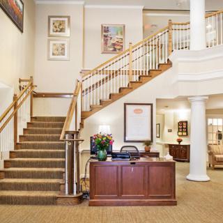 A hotel lobby featuring a grand staircase and a reception desk.