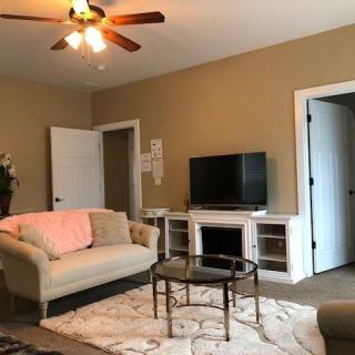 Cozy living room with a sofa, TV, and coffee table under a ceiling fan.