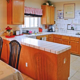 A cozy kitchen with wooden cabinets and a tiled countertop.