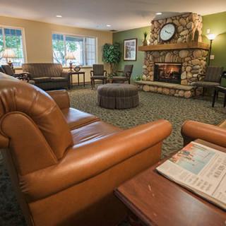 A cozy living room with a leather sofa and a stone fireplace, featuring a large clock and elegant interior design.